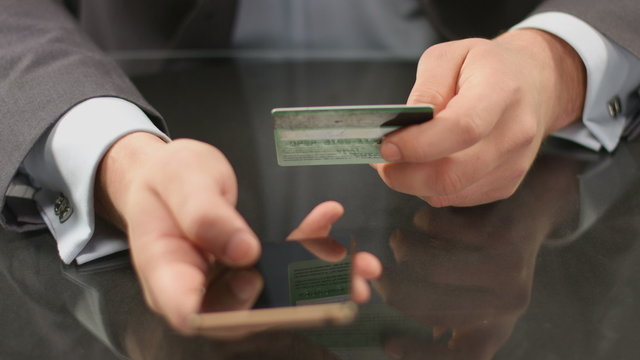 Top manager hands typing credit card number on smart phone