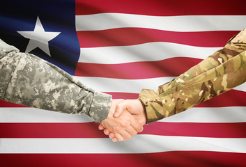 Men in uniform shaking hands with flag on background - Liberia