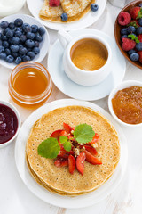 crepes with strawberry, jams and honey on white background, top