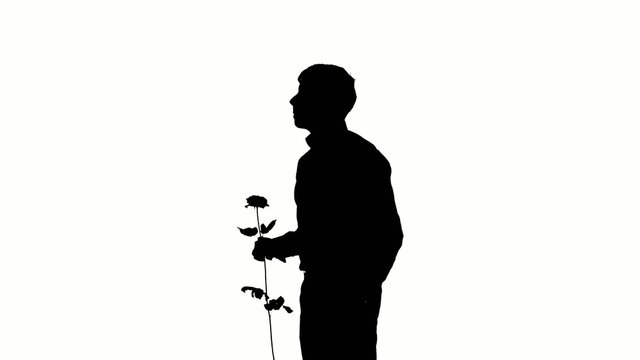 A man hiding a secret rose for his date. Silhouette. Slow motion