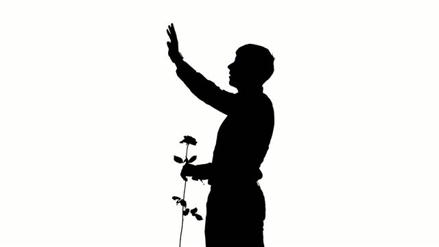 A man hiding a secret rose for his date. Silhouette. Slow motion
