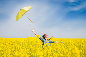 Young woman with an umbrella in canola field