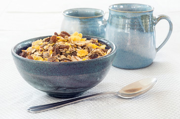 granola with raisins and blue pottery on a light gray tablecloth