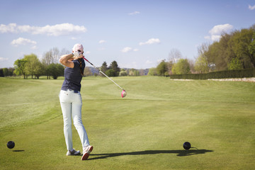 Female golf player swinging club.
