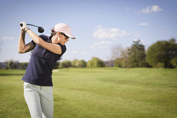 Close up of female golfer hitting golf ball.