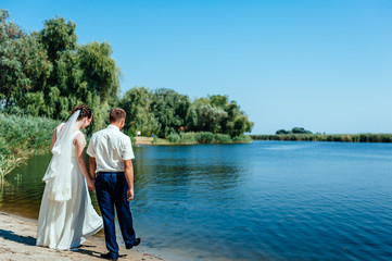 Fototapeta na wymiar A wedding by the sea. Honeymoon. The bride and groom hugging on