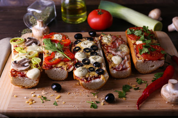 Different sandwiches with vegetables and cheese on cutting board on table close up