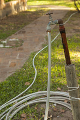 Old rusty water tap with hose in garden