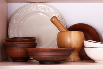 Kitchen utensils and tableware on wooden shelf