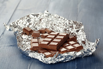Chocolate in foil on wooden table, closeup