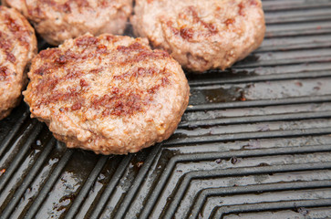 Beef burgers cooking on a metal griddle