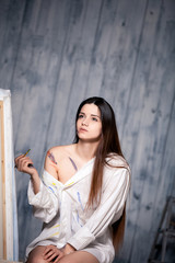 beautiful girl draws picture in the studio smeared with paint
