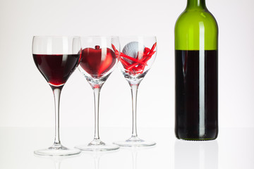 Wine glasses with red wine, heart and golf ball