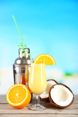 Glass of summer cocktail on wooden table on bright blurred background