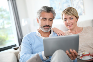 Middle-aged couple websurfing on internet with touchpad