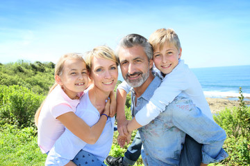 Parents giving piggyback ride to kids by the sea