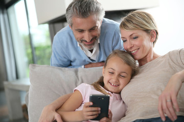 Parents watching daughter playing with smartphone