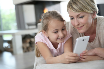 Mother and young girl playing with smartphone at home