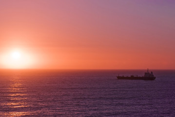 Silhouette of the cargo ship over the sunrise