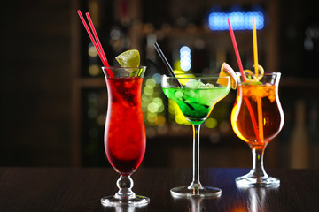 Glasses of cocktails on bar background