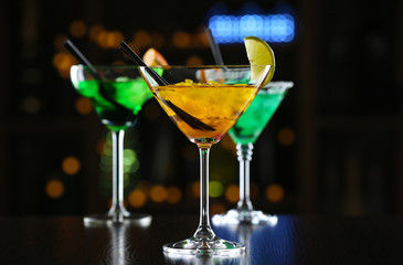 Glasses of cocktails on bar background