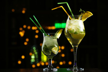 Glasses of cocktails on bar background