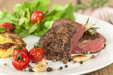 Filetsteak medium auf Teller mit Tomate und Kartoffelgratin
