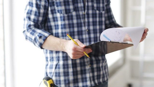 close up of man looking and writing to clipboard