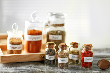 Assortment of spices in glass bottles on wooden background