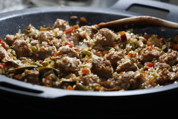 Meat, vegetables and rice on a black pan