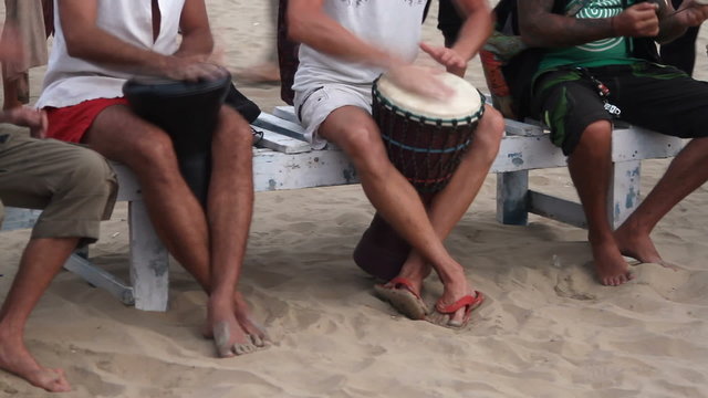 Unidentified man playing on drum at the beach