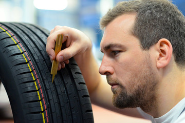 Automechaniker prüft Profiltiefe von Reifen