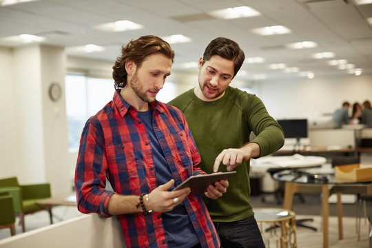 Two men looking at a digital tablet screen.
