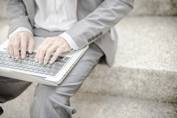 Businessman using laptop pc. He is sitting on a stairs.