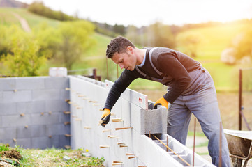 Bricklayer putting down another row of bricks in site