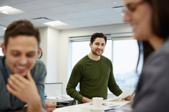 Three people in a large open plan office, two in the fore. 