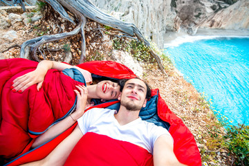 Young couple in sleeping bags near the sea
