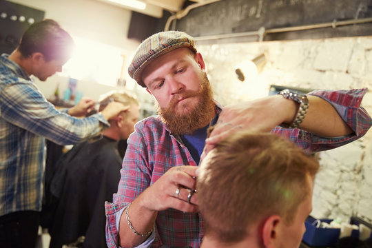 Male Barber Giving Client Haircut In Shop