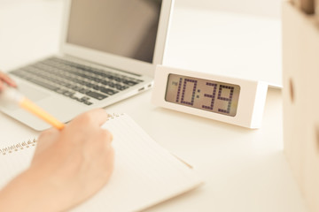 woman using her laptop with clock