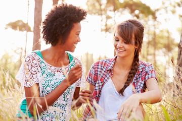 Obraz premium Portrait Of Two Smiling Young Women Sitting In Countryside