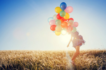 Beautiful woman with colorful balloons outside.