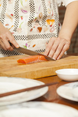 Obraz na płótnie Canvas an Asian woman chef preparing salmon piece with sharp knife