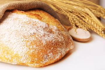 Fresh bread with wheat and wooden spoon of flour, closeup
