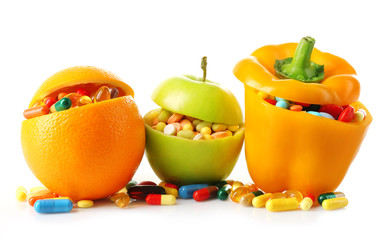 Orange fruit, apple and bell-pepper and colorful pills, isolated on white