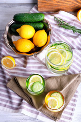 Fototapeta na wymiar Fresh water with lemon and cucumber in glassware on napkin, top view