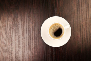 Cup of coffee on wooden table, top view