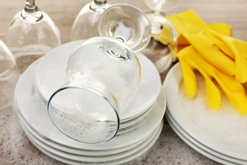 Dishes in foam with gloves on table close up