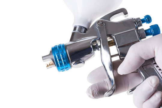 A painter's arm hand holding industrial size spray gun used for