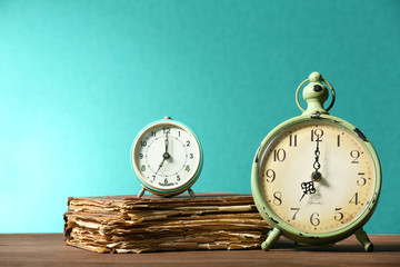 Retro clock with old book on table on green background
