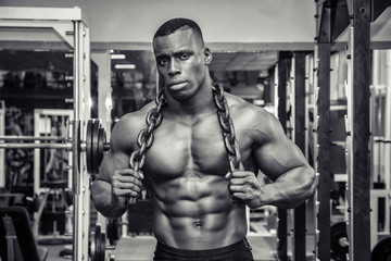 Fototapeta na wymiar Attractive hunky black male bodybuilder posing with iron chains